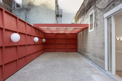 Outdoor courtyard enclosed by red-hued panels and a pergola