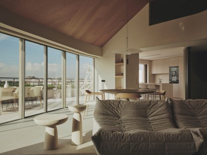 Photograph of an open-plan living and dining space with a large glass facade offering views of Valencia city
