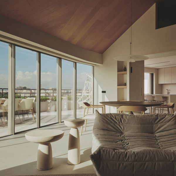 Photograph of an open-plan living and dining space with a large glass facade offering views of Valencia city