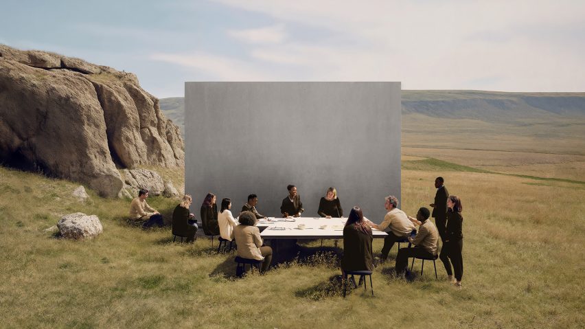Photo of people sat around a table in front of a monolith in grass