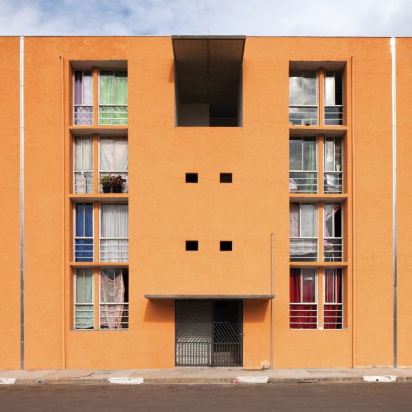 A photograph of an orange building with large rectangular windows.