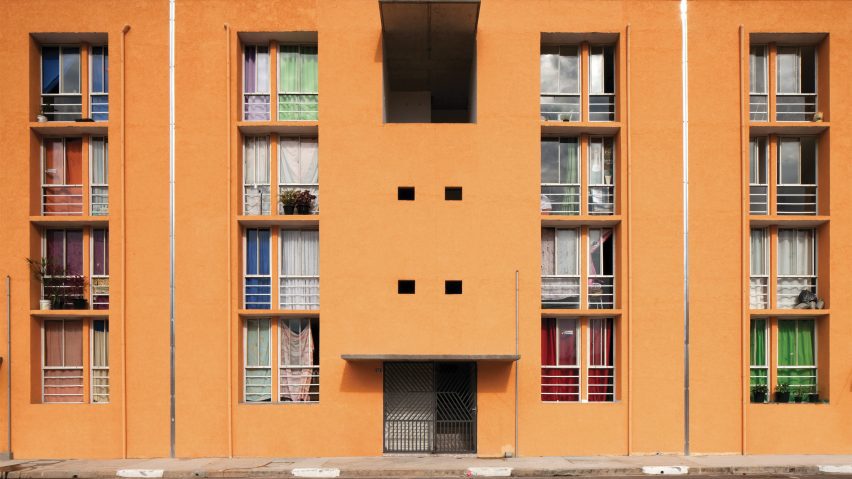 A photograph of an orange building with large rectangular windows.