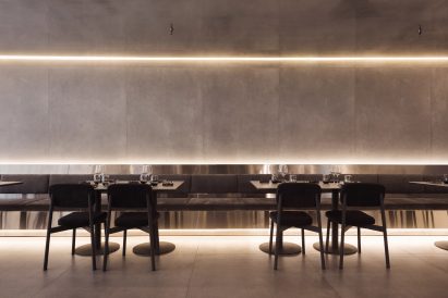 A metal banquette running along a wall, with cove lighting installed along the horizontal edges of the space