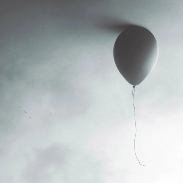 Grey balloon floating in front of grey background