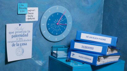 A photograph displaying a stack of ring binder folders on a table, with a clock and pieces of paper on the wall behind them. All the objects are in tones of blue.