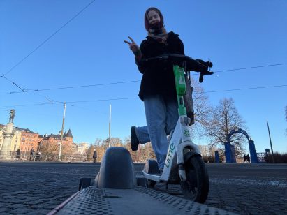 Woman on lime scooter in front of sunny blue sky