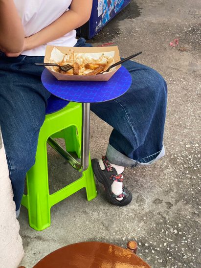 Person sitting and eating on a green stool
