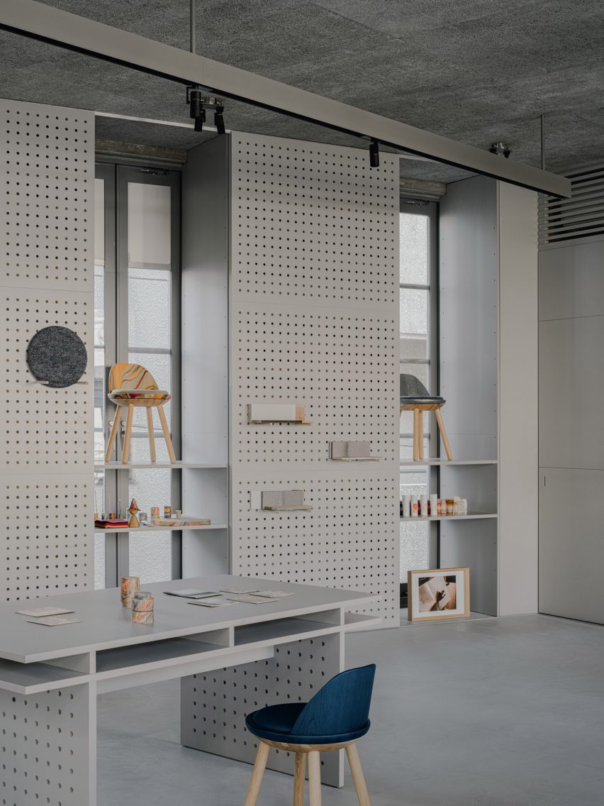 Perforated metal panels with items on display alongside chair and desk