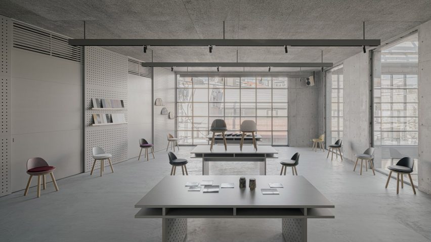 Desks and chairs in concrete room with glass windows