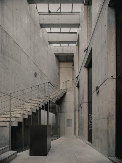 Concrete entrance hallway atrium with staircase and skylights