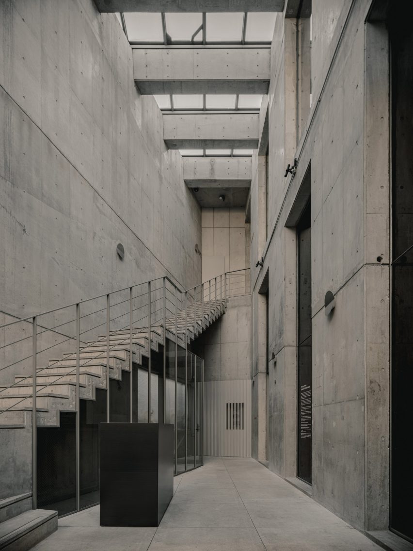 Concrete entrance hallway atrium with staircase and skylights