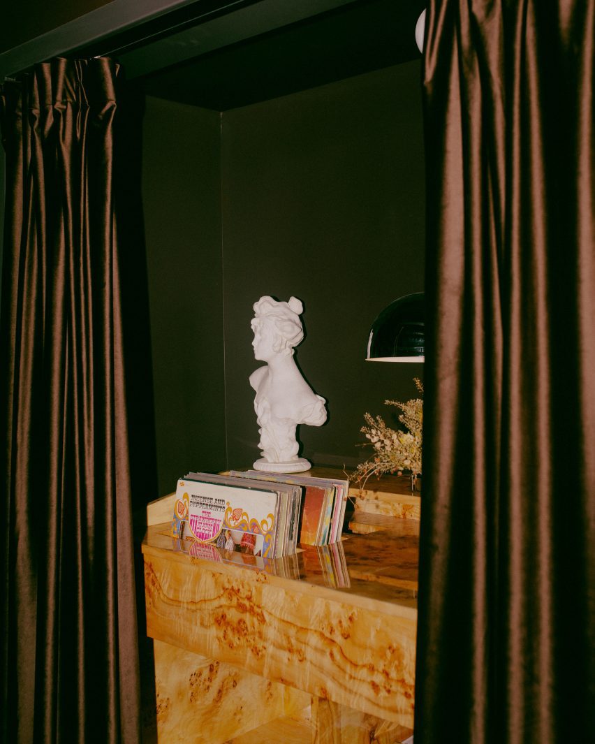 Records in wooden holder behind brown curtains