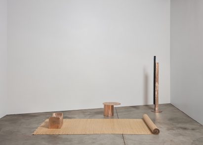 Photo of three copper objects laid out within a bare gallery space