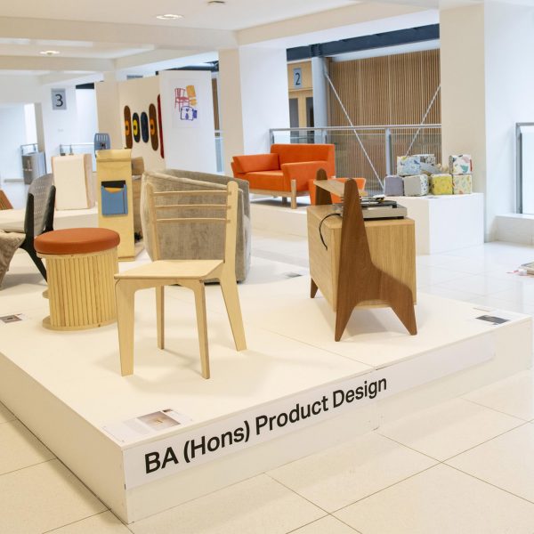 A photograph of a student exhibition in tones of beige and white.