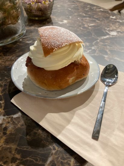 cream bun on a saucer with a teaspoon