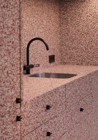 Speckled red kitchen in showroom by Note Design Studio