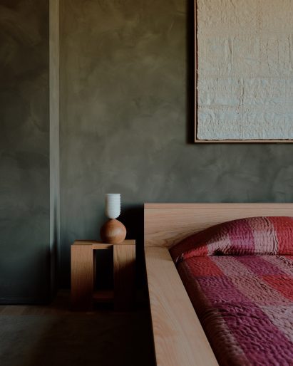 Green limewash paint provides a backdrop for monolithic bedroom furniture