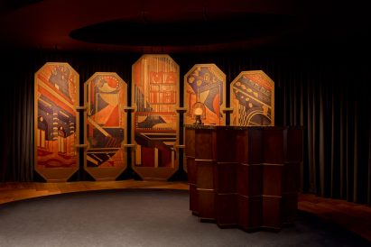 Illustrated panels behind a host stand depicting scenes of the theatre district below