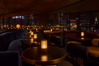 Dimly lit lounge with seats facing a view of the Manhattan skyline
