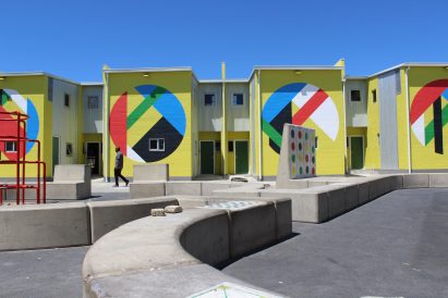 Photo of yellow terrace houses painted with bright geometric murals at the BT-Soweto development by UTTE Empower