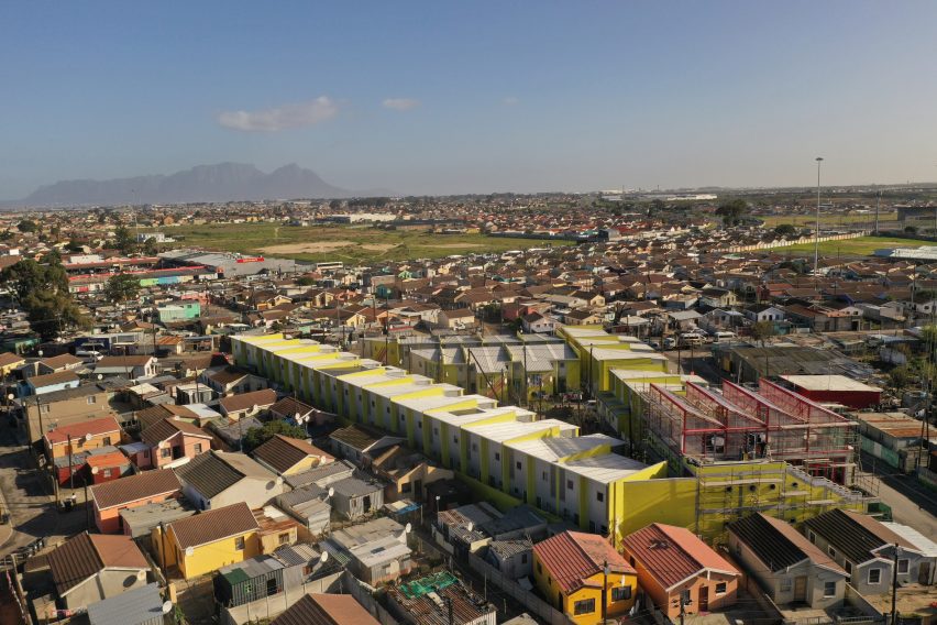 Aerial view of the UTT Empower BT-Soweto development, appearing like a triangle of acid yellow terrace housing amid a neighbourhood of mostly low-quality homes