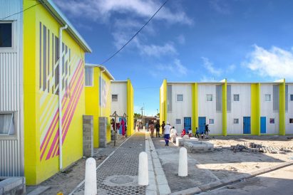 Photo of the facades of several row houses with facades combining corrugated metal and nrightly painted concrete block walls.