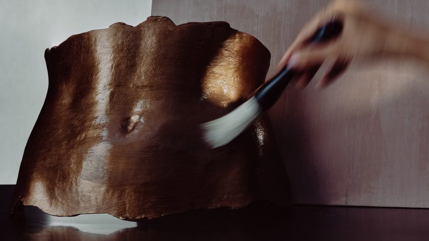 Photo of hand brushing torso sculpture