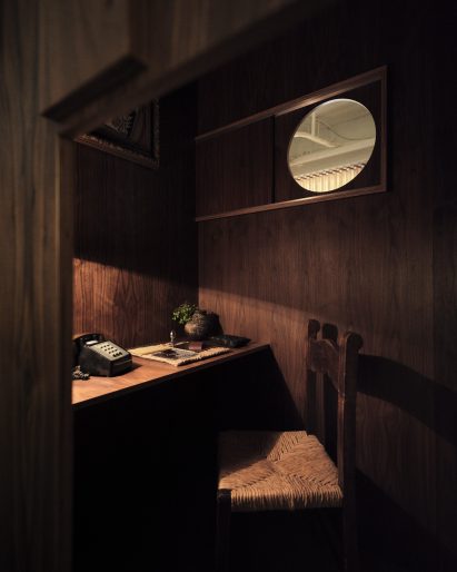 A custom phone booth in dark wood with a porthole