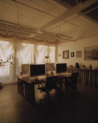 Work area with four desks clustered in the centre, with a yellow curtain over the window