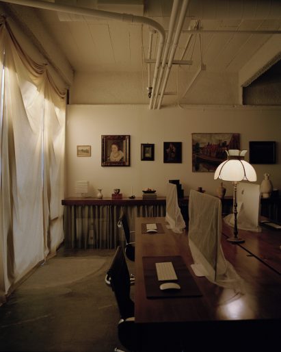 Wood desks clustered in the centre of a room, with a chainmail skirt along the wall