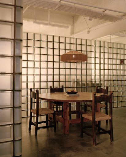 Glass-block partitions defining a dining room with a wood table and four chairs