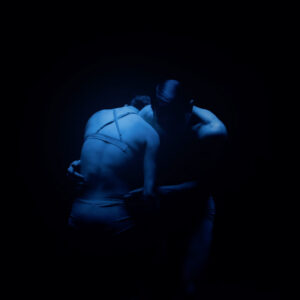 Two figures lit with blue light in a dark space