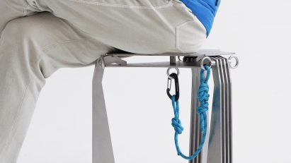 A photograph of a person sat on a silver stool