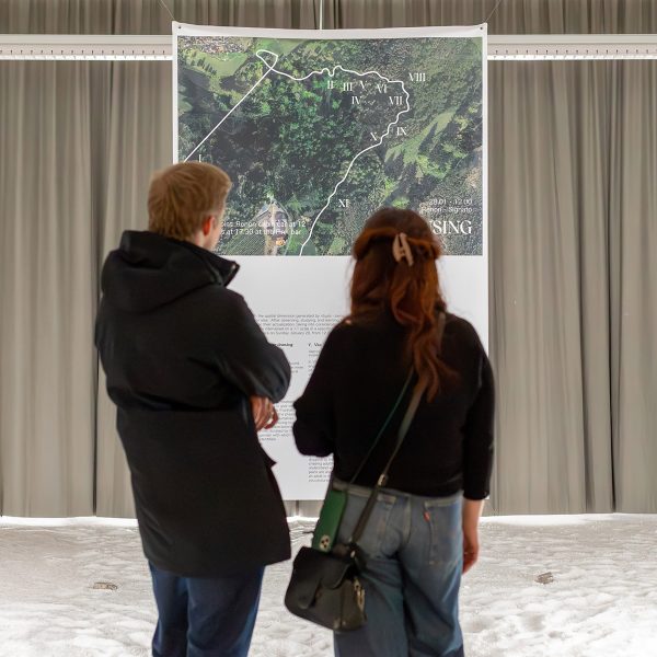 A photograph of two people looking at a piece of art in tones of green and beige