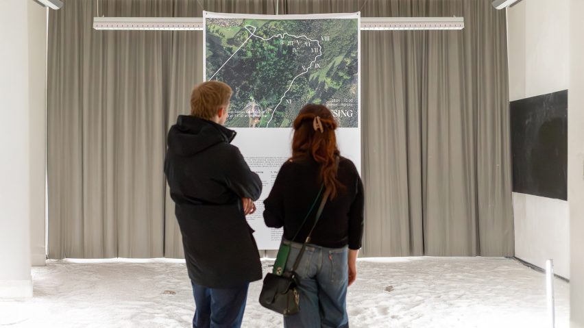 A photograph of two people looking at a piece of art in tones of green and beige