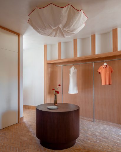 A drum-shaped walnut podium below a ruched-fabric lamp