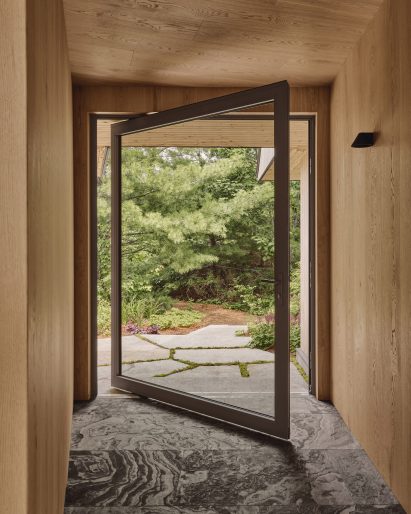 Alarge glass door pivots open to a garden