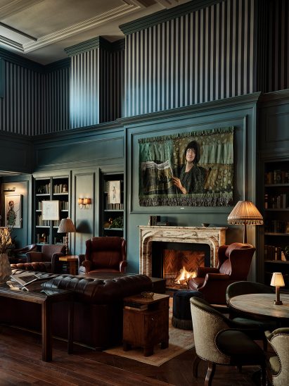 Cosy lounge area with teal walls, open fire and tall ceilings