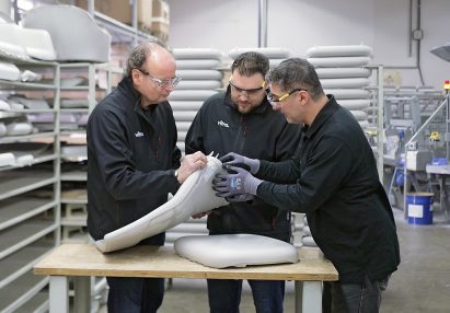 Photo of three men inspecting a piece of polyurethane foam in a factory