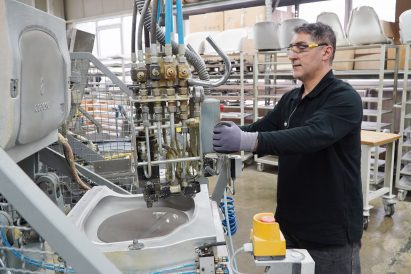 Photo of a man handling a machine injecting a grey substance into a mould in a factory