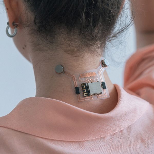 a photograph of a person wearing an electronic device on the back of their neck