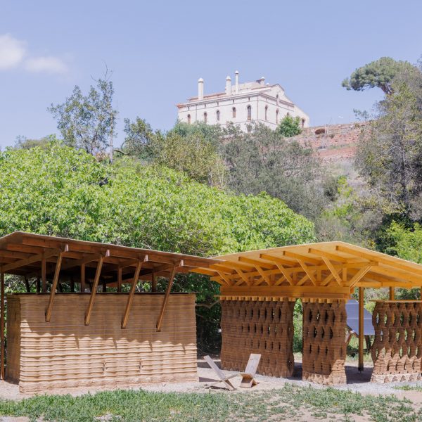a photograph of a beige wooden structure amongst greenery