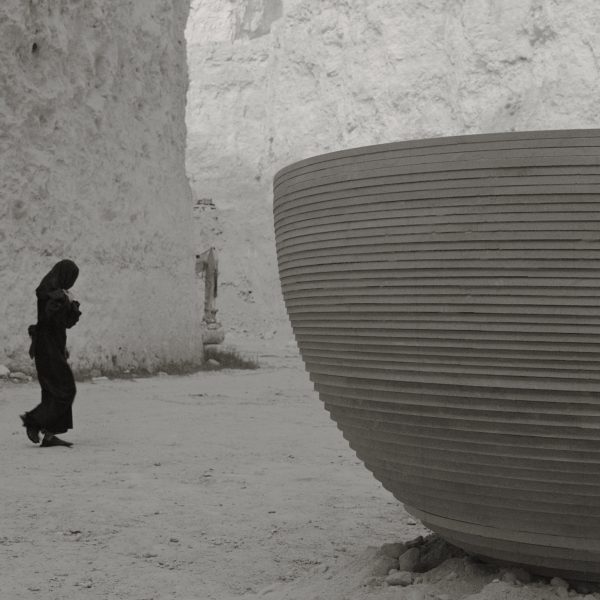 Photo of person walking near bowl-shaped installation with ribbed texture