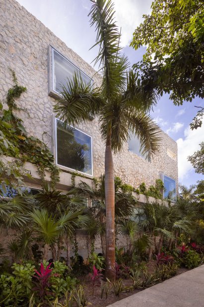 Exterior of home with limestone walls and tropical planting