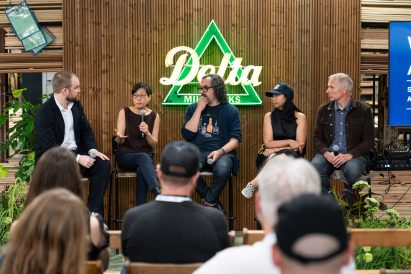 Photo of participants speaking on a panel at Delta Millworks, with Katherine Chia speaking into the microphone