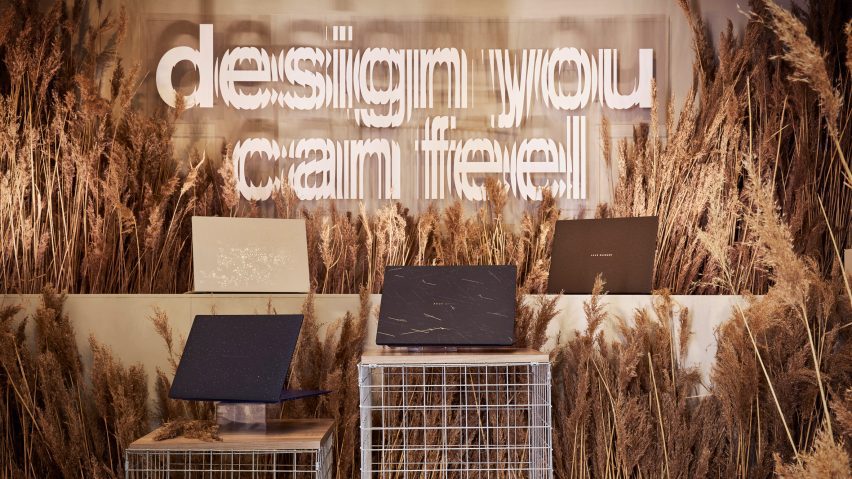Four of ASUS's Ceraluminum Signature Edition Zenbook laptops on plinths surrounded by wheat