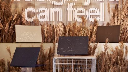 Four of ASUS's Ceraluminum Signature Edition Zenbook laptops on plinths surrounded by wheat
