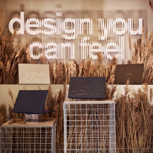 Four of ASUS's Ceraluminum Signature Edition Zenbook laptops on plinths surrounded by wheat