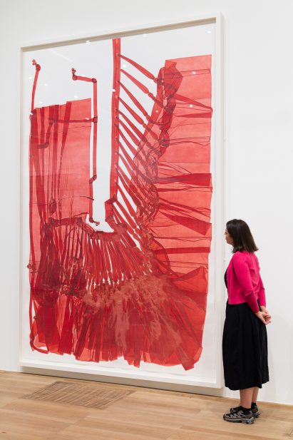 Woman watching red artpiece by Do Ho Suh