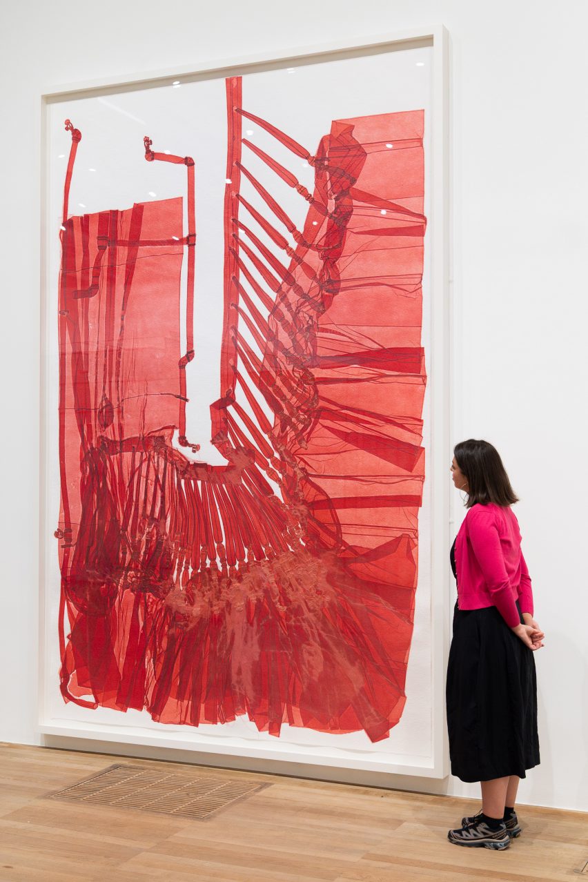 Woman watching red artpiece by Do Ho Suh